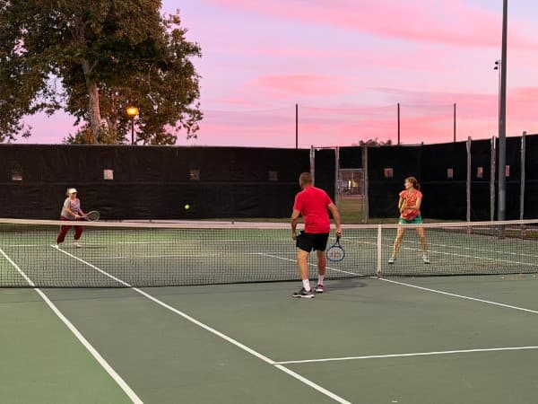 Adults playing doubles at golden hour